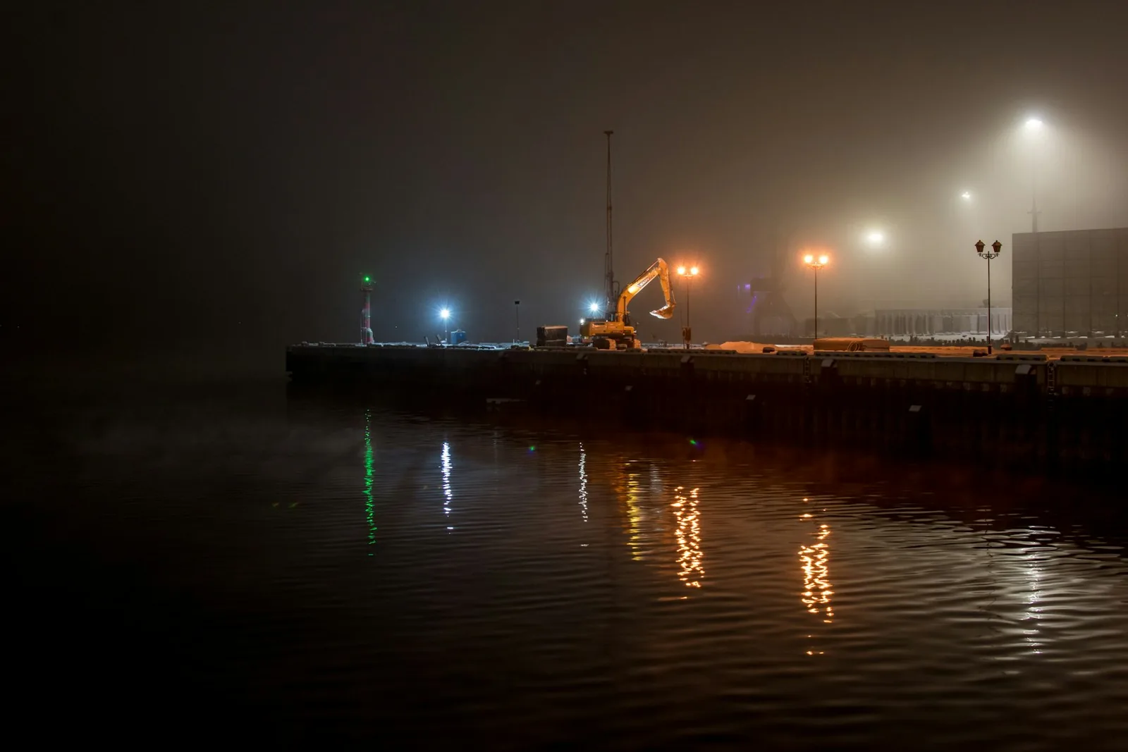 A quay at night, harbour lights reflected on still water